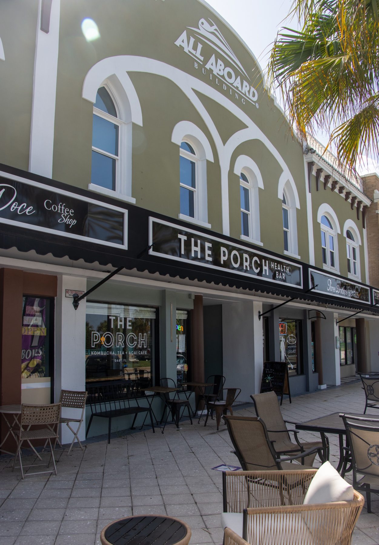 The Porch cafe storefront with outdoor seating under a black awning